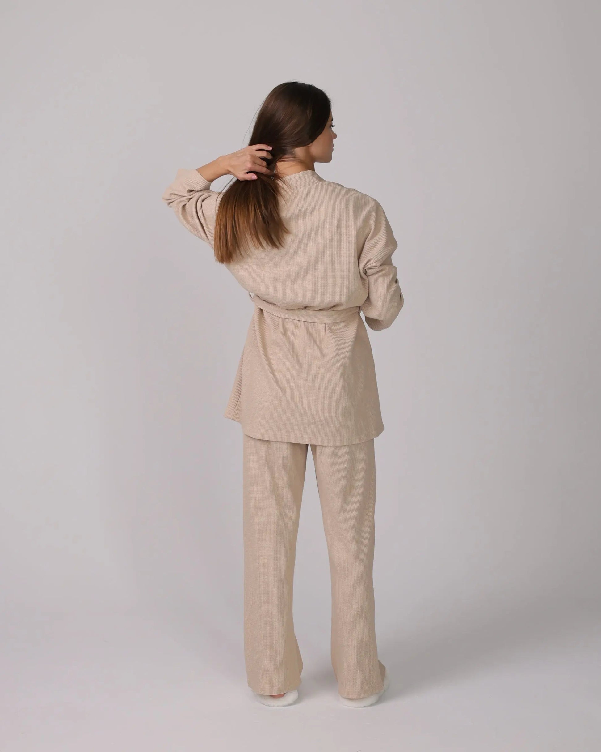 1. Woman wearing a beige 3-piece loungewear set with cardigan, top, and pants.
 2. Close-up of soft cotton fabric in the loungewear set.
 3. Loungewear set displayed neatly with shorts option on a minimalist background.
 4. Woman sitting on a sofa, relaxing in the cotton loungewear.