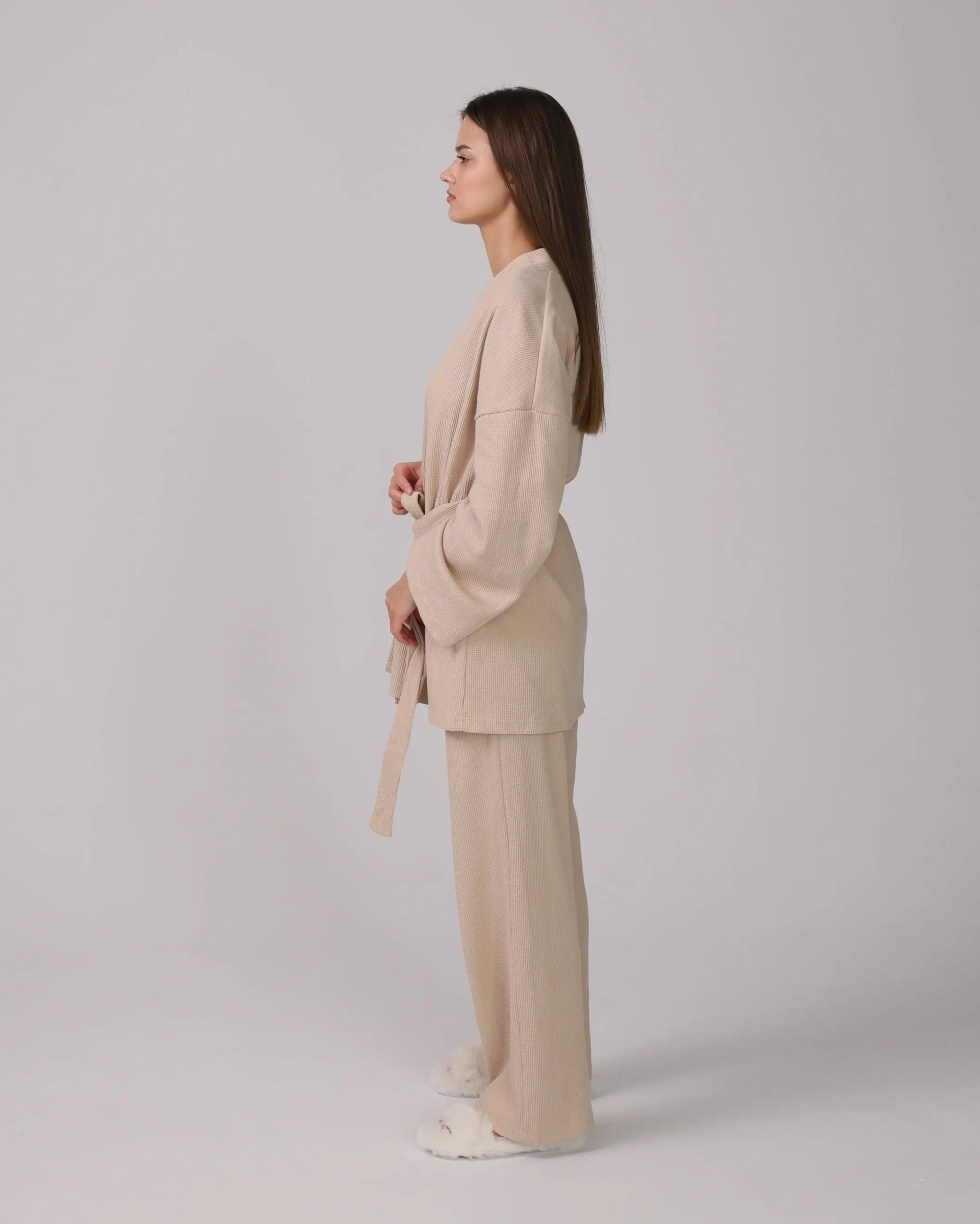 1. Woman wearing a beige 3-piece loungewear set with cardigan, top, and pants.
 2. Close-up of soft cotton fabric in the loungewear set.
 3. Loungewear set displayed neatly with shorts option on a minimalist background.
 4. Woman sitting on a sofa, relaxing in the cotton loungewear.