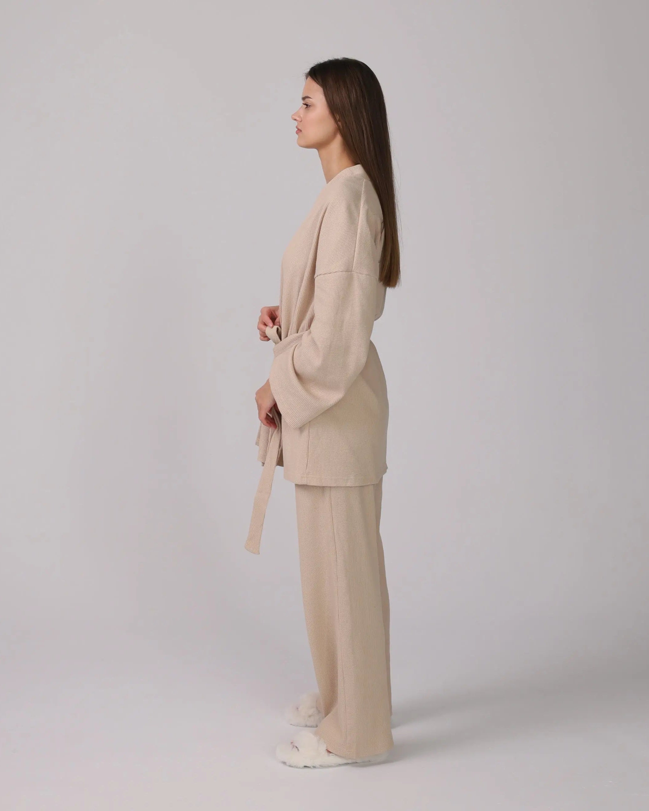 1. Woman wearing a beige 3-piece loungewear set with cardigan, top, and pants.
 2. Close-up of soft cotton fabric in the loungewear set.
 3. Loungewear set displayed neatly with shorts option on a minimalist background.
 4. Woman sitting on a sofa, relaxing in the cotton loungewear.