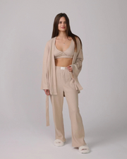 1. Woman wearing a beige 3-piece loungewear set with cardigan, top, and pants.
 2. Close-up of soft cotton fabric in the loungewear set.
 3. Loungewear set displayed neatly with shorts option on a minimalist background.
 4. Woman sitting on a sofa, relaxing in the cotton loungewear.