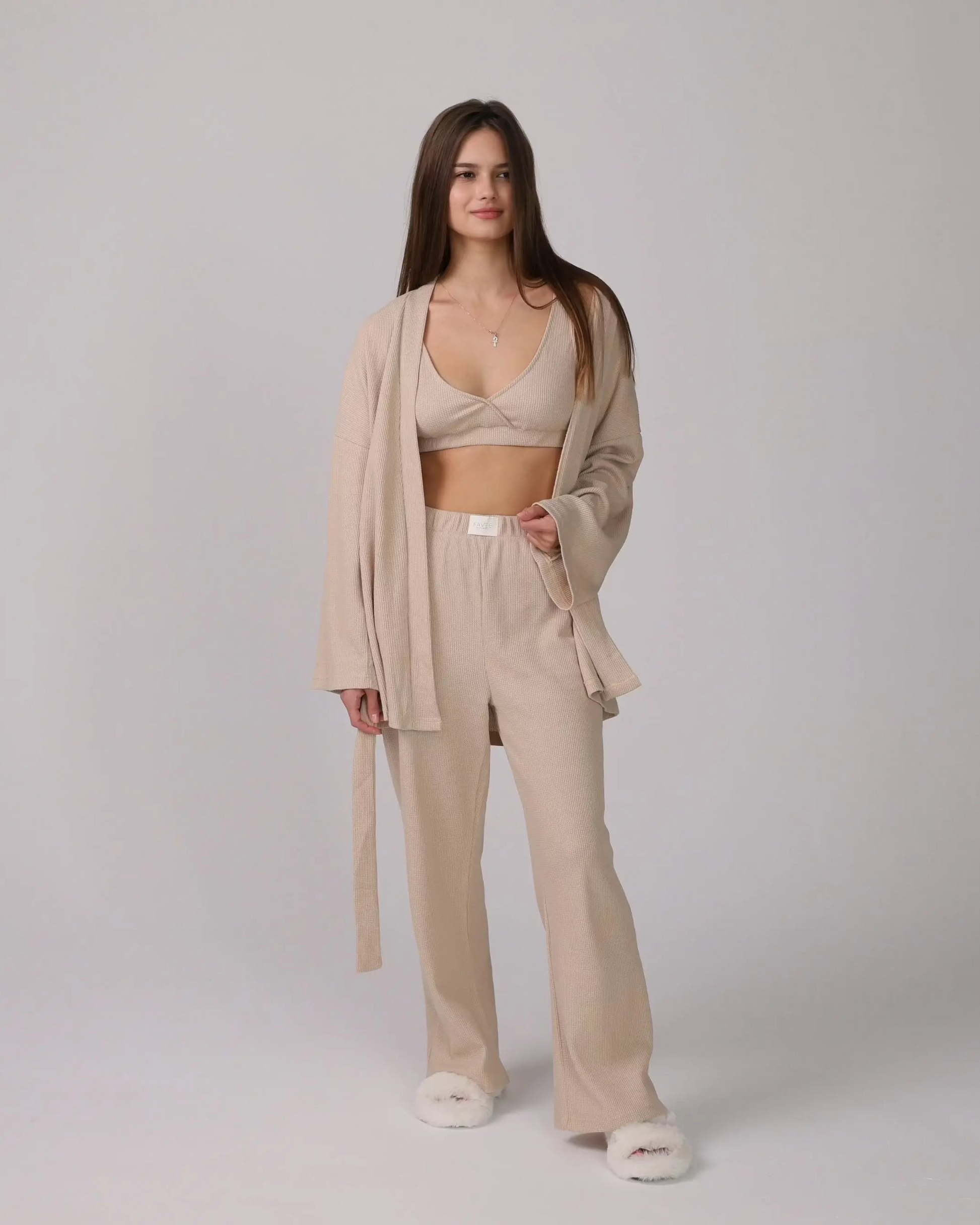1. Woman wearing a beige 3-piece loungewear set with cardigan, top, and pants.
 2. Close-up of soft cotton fabric in the loungewear set.
 3. Loungewear set displayed neatly with shorts option on a minimalist background.
 4. Woman sitting on a sofa, relaxing in the cotton loungewear.